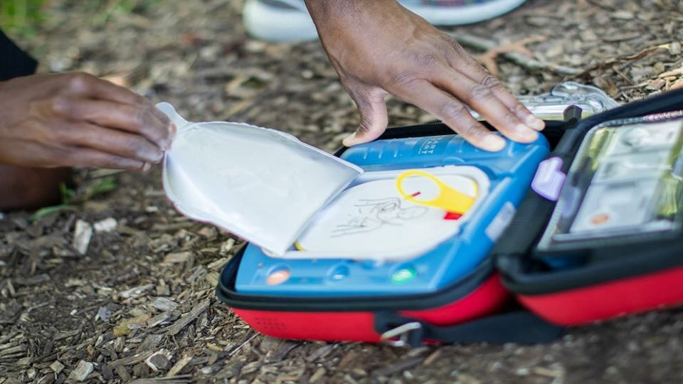 A bystander taking the pads out of a HeartStart AED outdoors